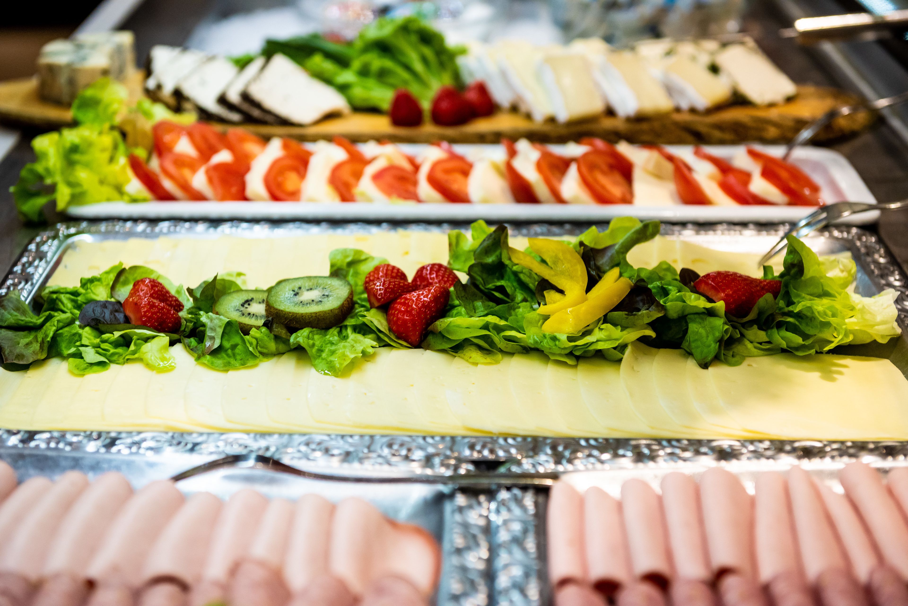 A buffet with various food items including sliced meats, fruits, and vegetables.