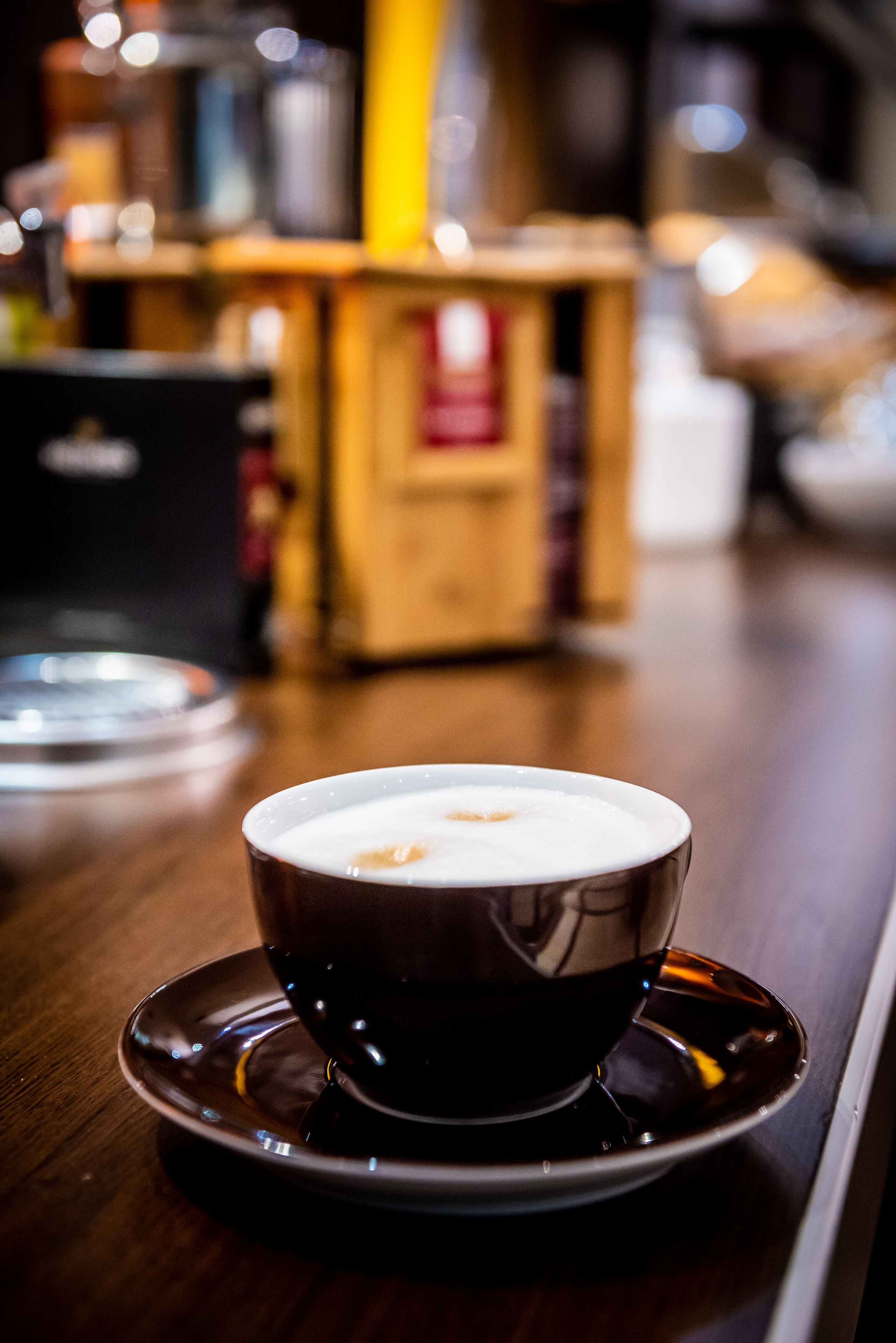 Eine Kaffeetasse auf einem Untertasse vor unscharfem Hintergrund einer Bar.