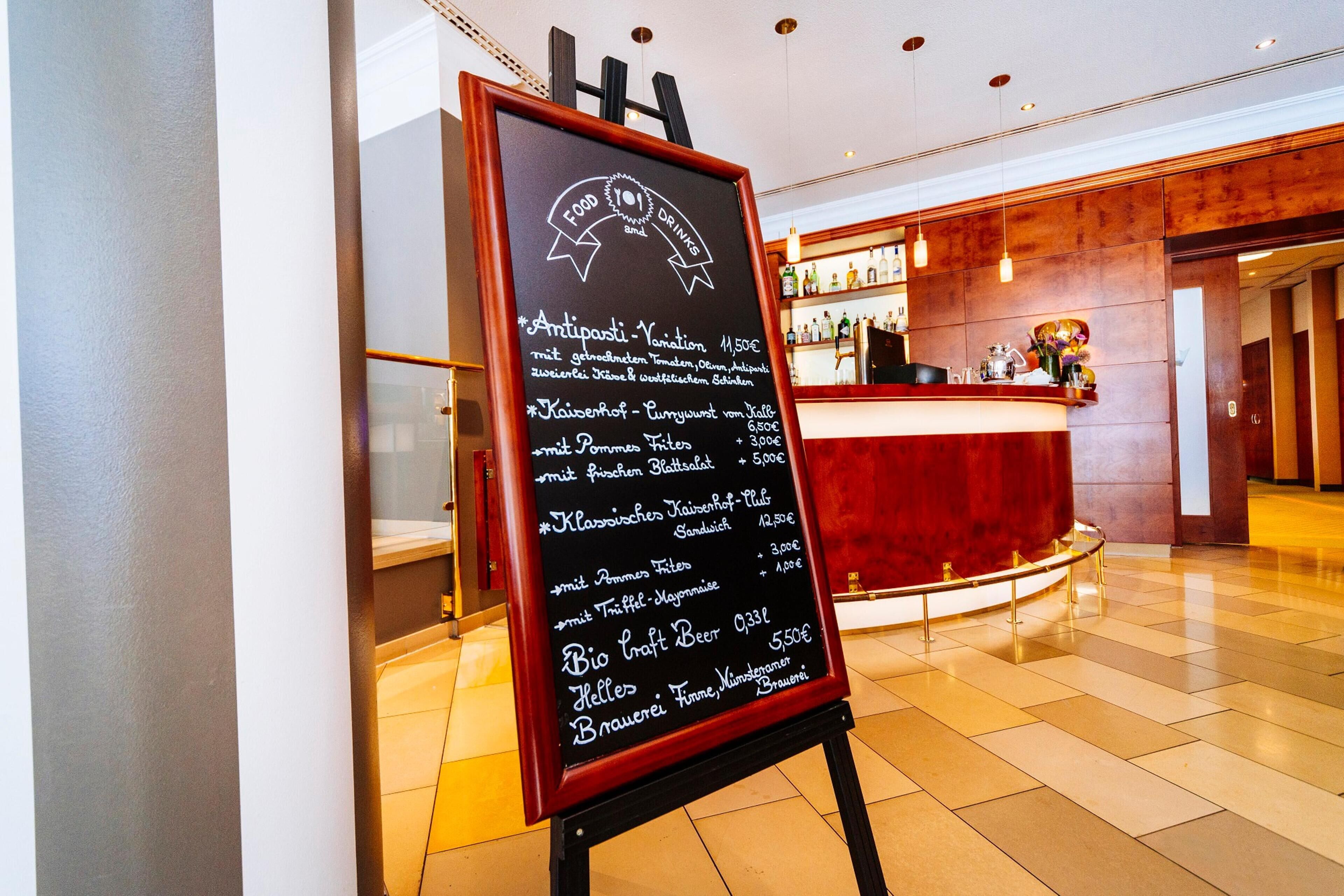Een schoolbordmenu met prijzen van gerechten en dranken in de hotelhal.