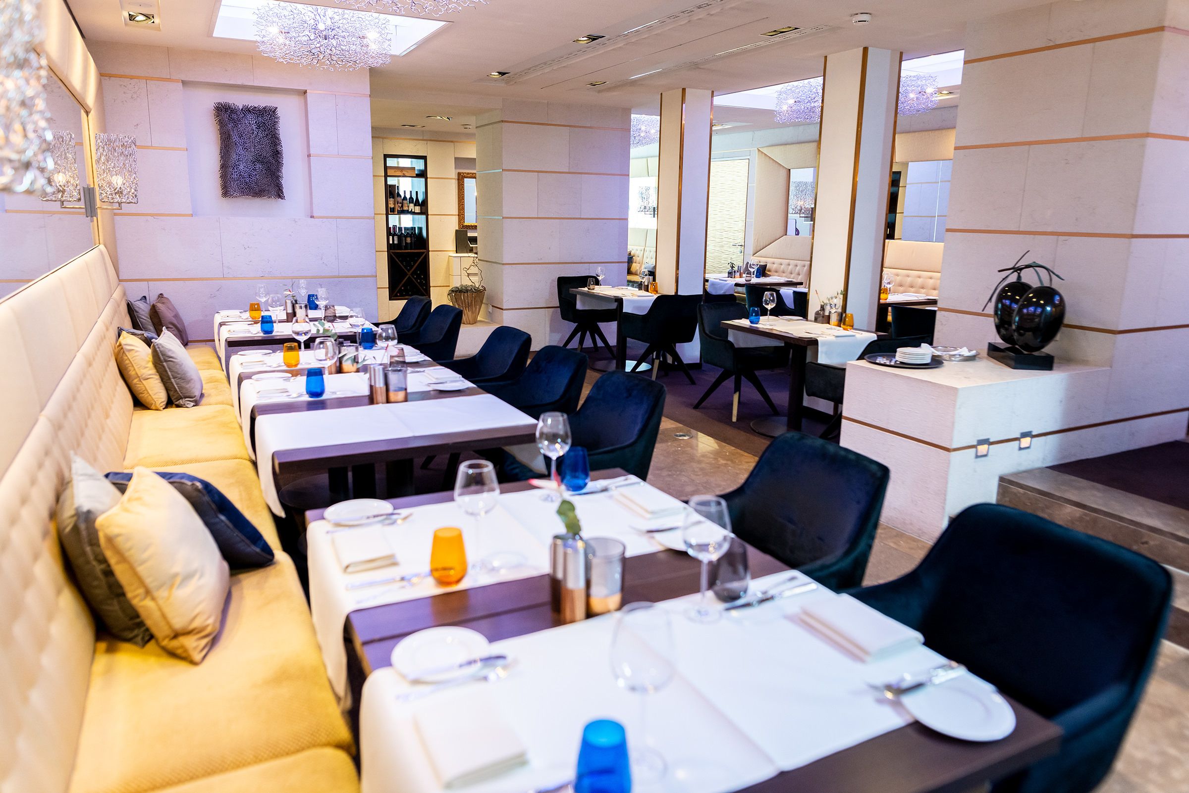 Un restaurant moderne doté de plusieurs tables, de sièges confortables et d’un bar.