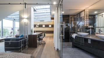 Et moderne hotelværelse med en stor seng, et skrivebord og et badeværelse med en stor vask og et spejl.