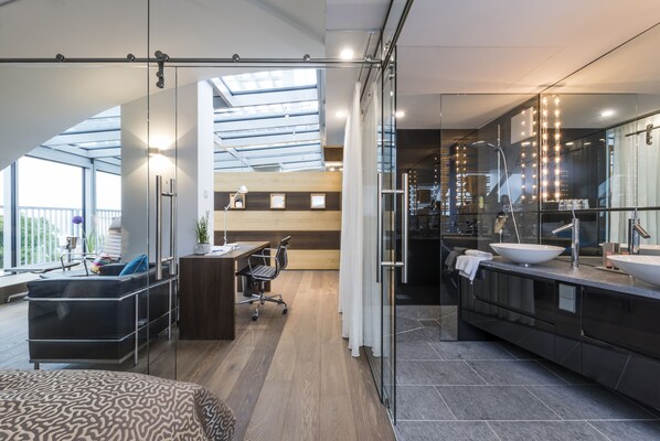 Una habitación de hotel moderna con una cama grande, un escritorio y un baño con un lavamanos grande y un espejo.