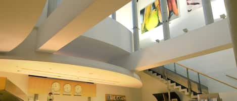 A spacious interior with a high ceiling, a central staircase, and a seating area with a table and chairs.