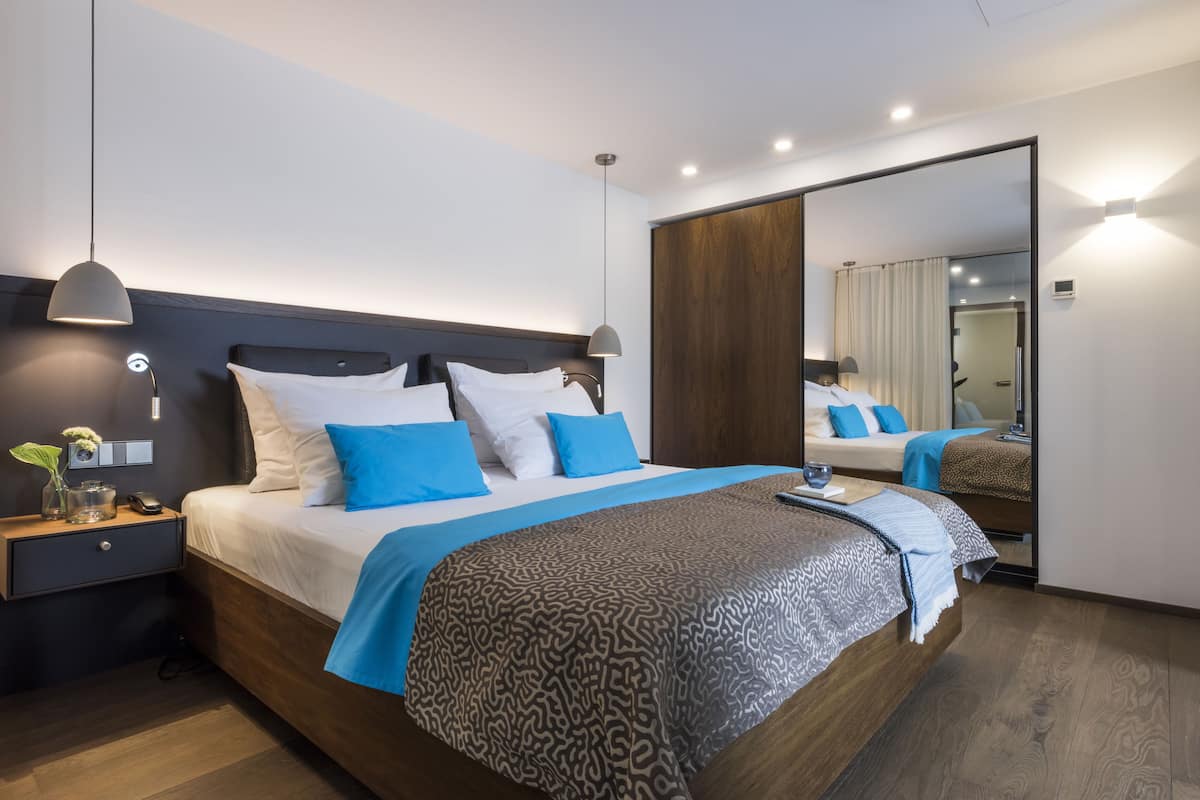 Een moderne hotelkamer met een groot bed, nachtkastjes, een spiegel en een nachtkastje.