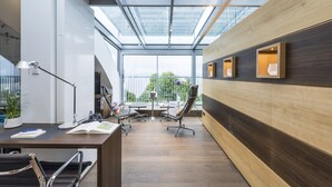 Un espacio de oficina moderno con tragaluces, paneles de madera y un escritorio con sillas de oficina.
