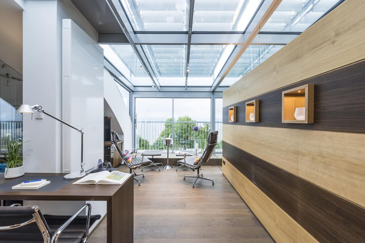 Een moderne kantoorruimte met dakraam, houten lambrisering en een bureau met bureaustoelen.