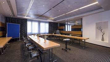 A conference room with long tables, chairs, and a projector.