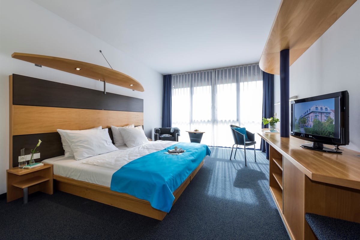 Een hotelkamer met een bed, een bureau, een televisie en een raam met gordijnen.
