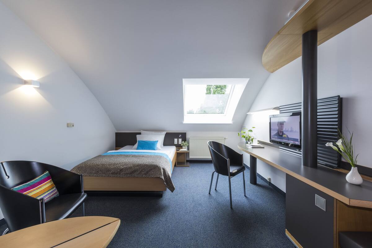 Een moderne slaapkamer met een bed, een bureau, een stoel en een televisie.