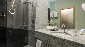 A modern bathroom with a granite countertop, a glass-enclosed shower, and a visible towel rack.