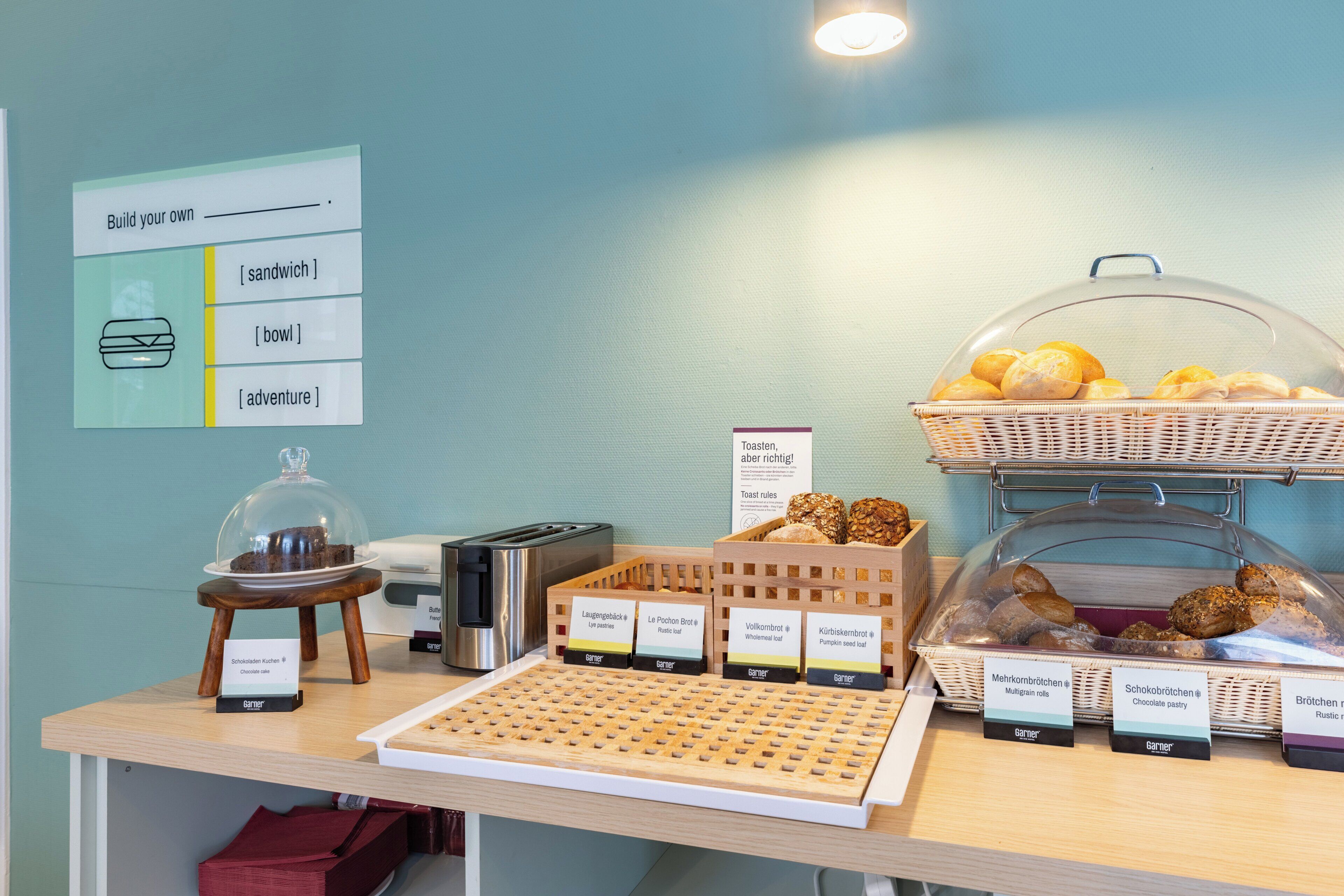 A bakery display with various baked goods and a sandwich-making station.
