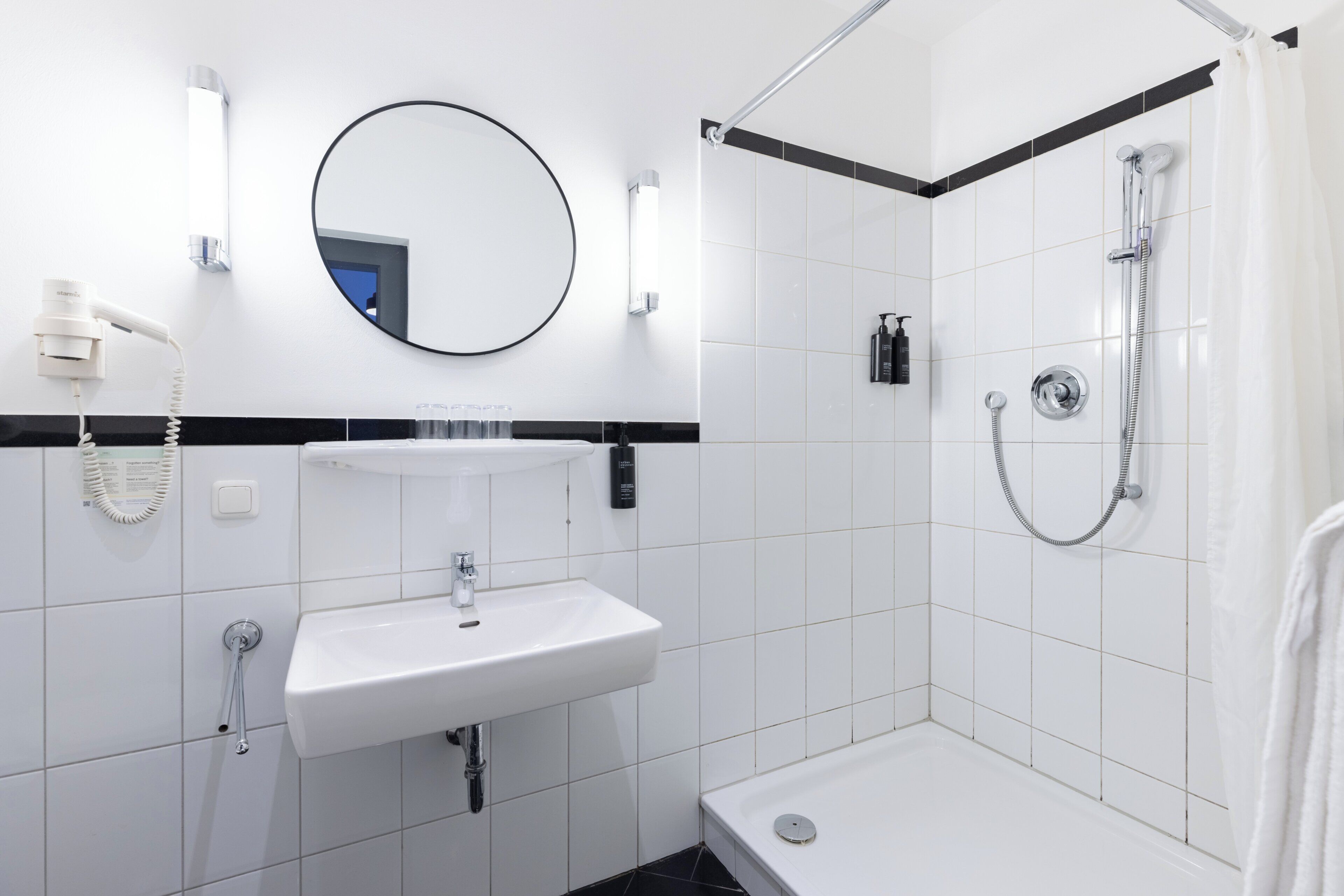 A modern bathroom with a white sink, mirror, and shower.