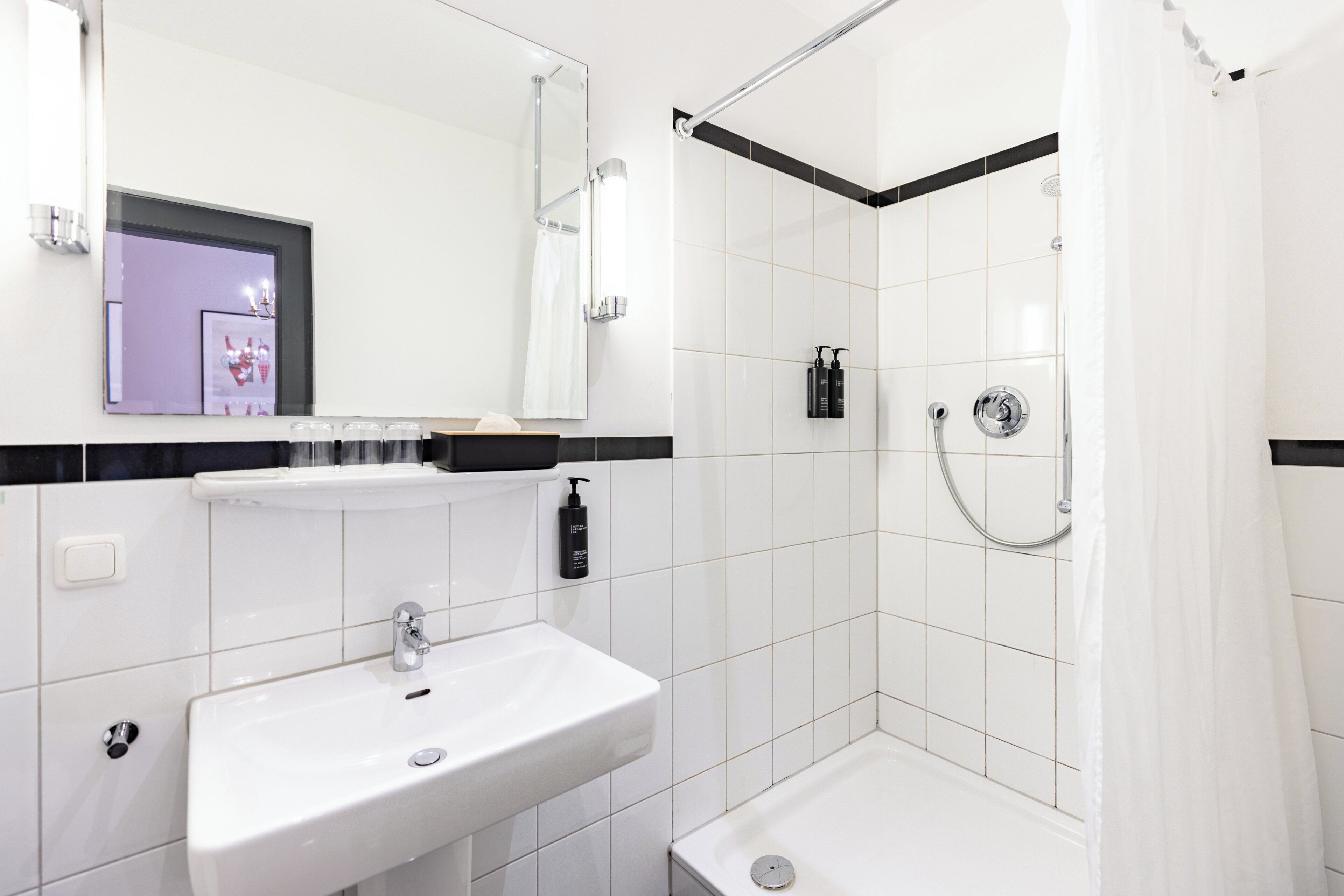 Un baño moderno con lavamanos, espejo y ducha blancos.