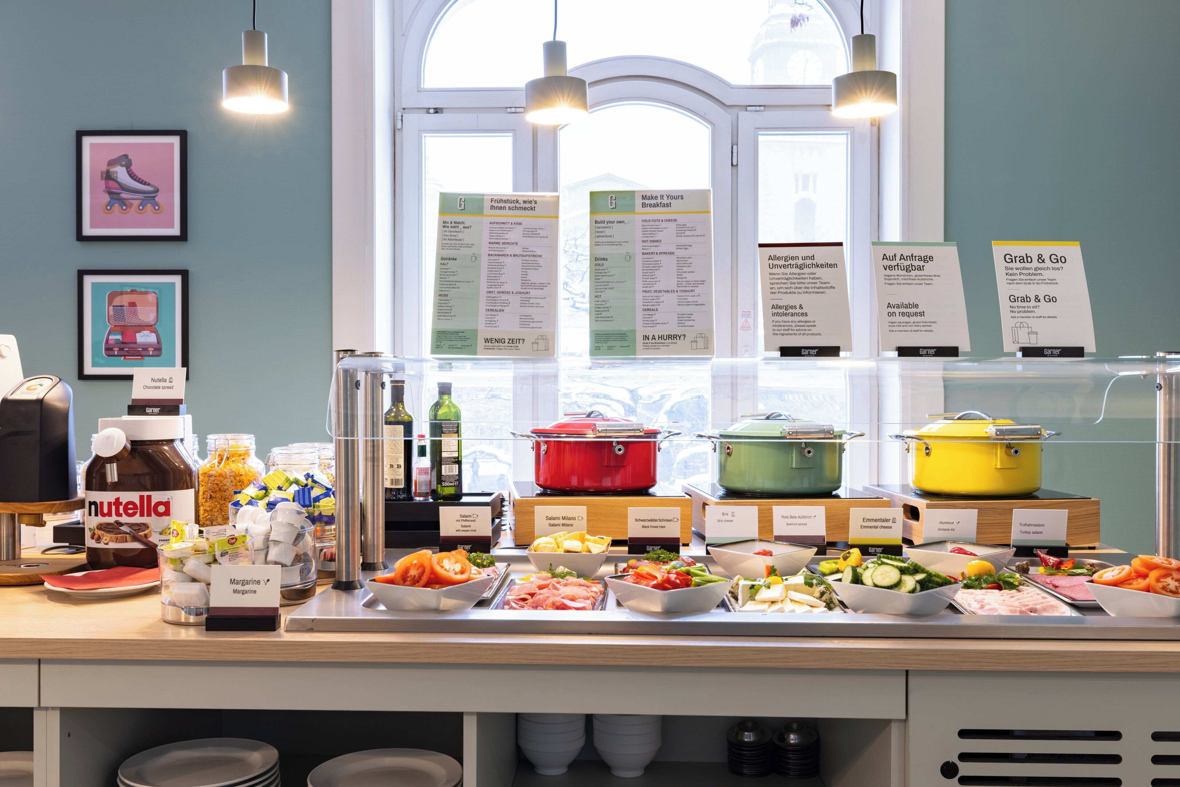A buffet with various food items and condiments, a window with natural light, and informational signs.
