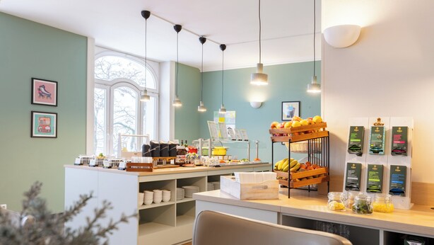 Una barra de desayuno con diferentes opciones de alimentos, una estación de café y una zona de estar con vistas al exterior.