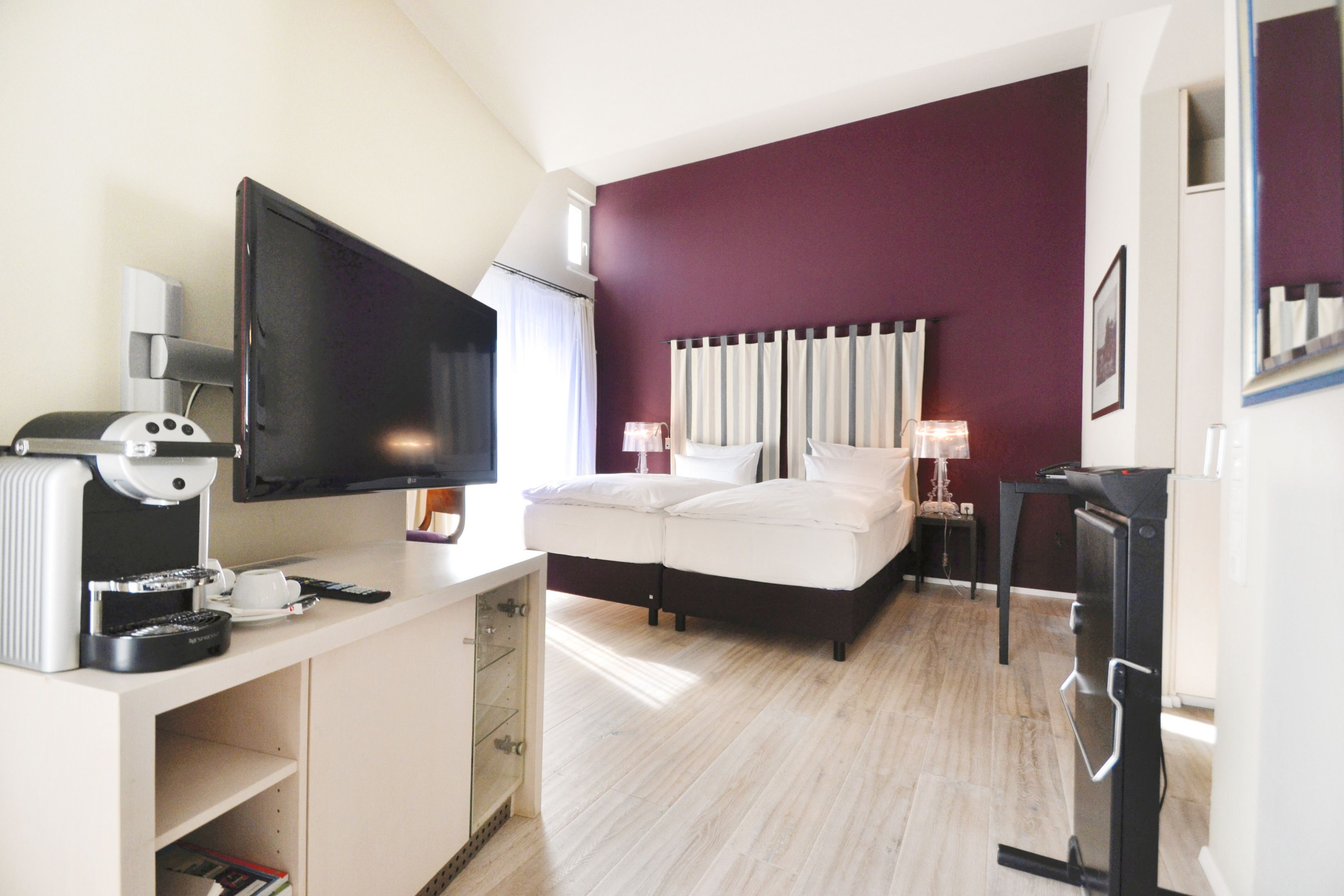 Una habitación de hotel con cama, televisión, escritorio con cafetera y refrigerador.