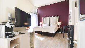 Una habitación de hotel con cama, televisión, escritorio con cafetera y refrigerador.