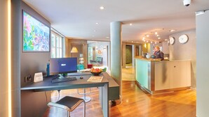 Een hotel receptie met een balie, computer en zitplaatsen.