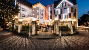 Een modern gebouw met een centrale binnenplaats, terrasjes en een zichtbaar restaurantschild.