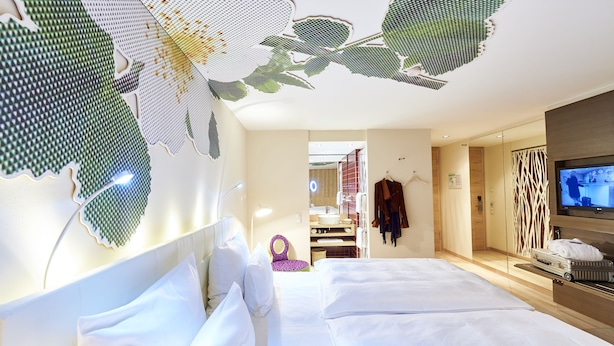 Een hotelkamer met een groot bed, een televisie en een bijzonder plafondontwerp.