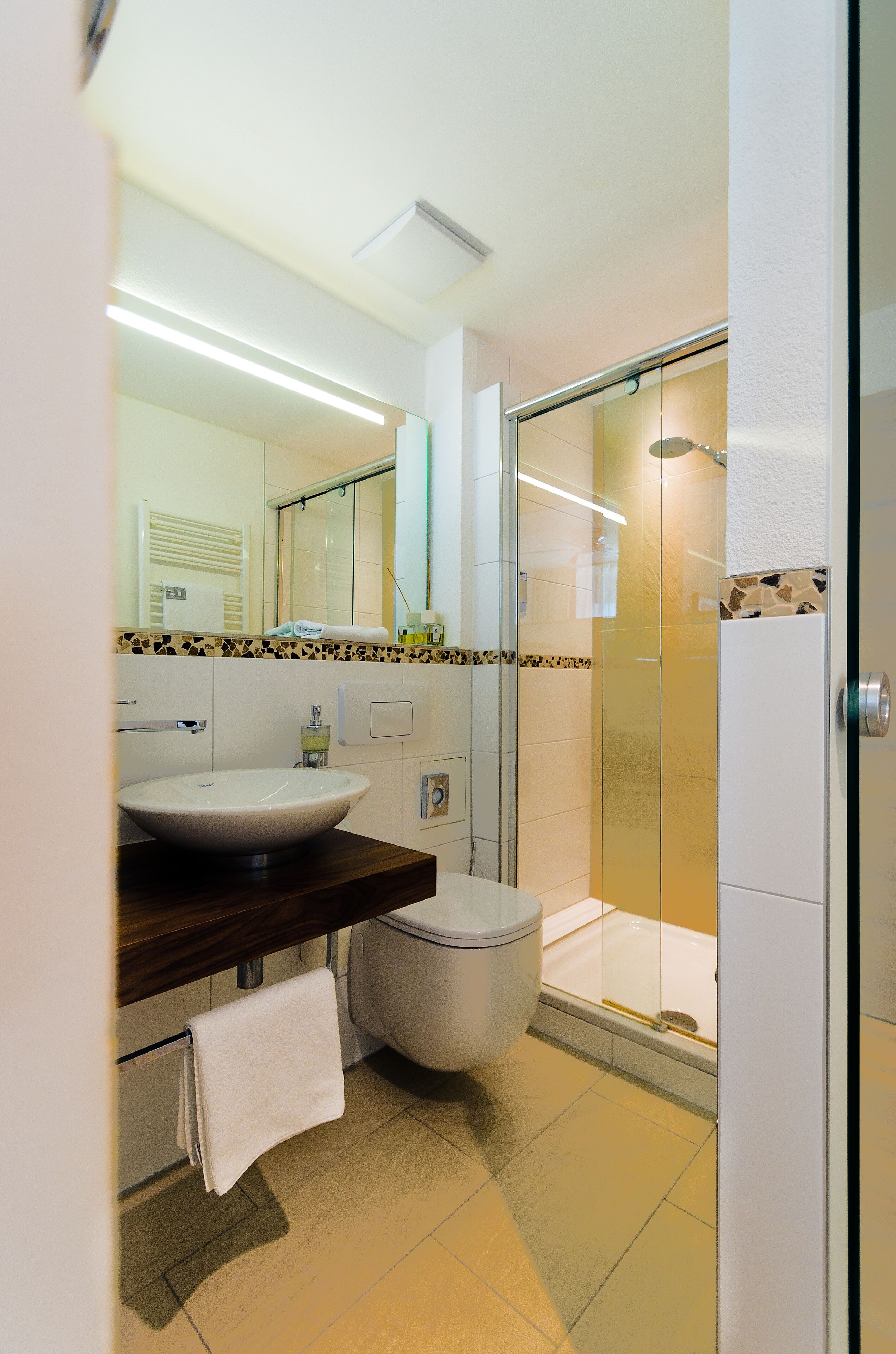 A modern bathroom with a large sink, toilet, and glass-enclosed shower.