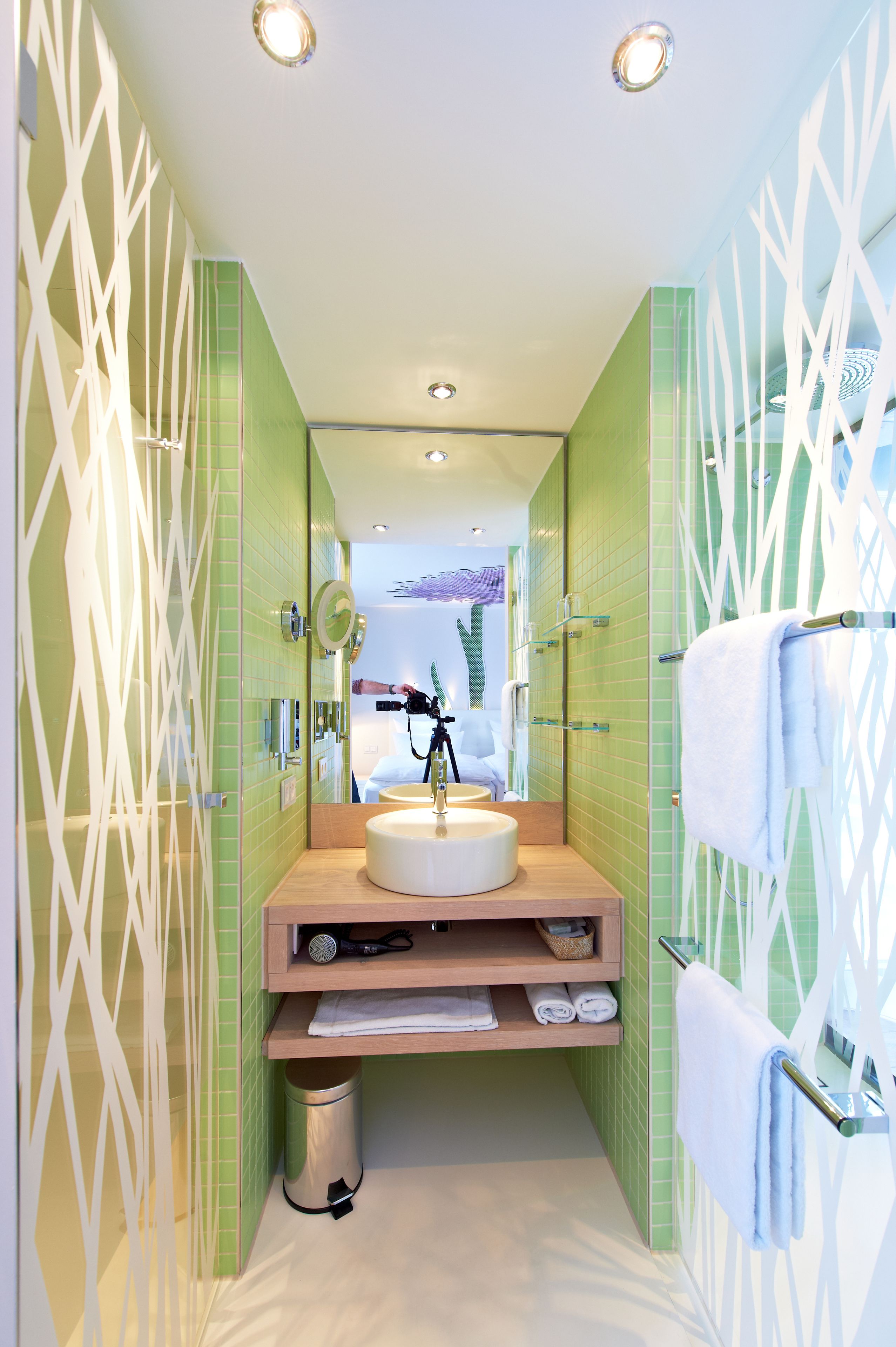 Un baño moderno con un lavabo redondo, un espejo y un perchero para toallas.