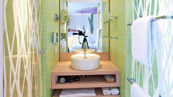 Un baño moderno con un lavabo redondo, un espejo y un perchero para toallas.