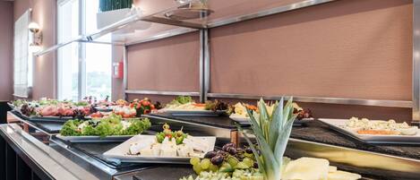 A buffet with various food items including fruits, cheeses, and salads.