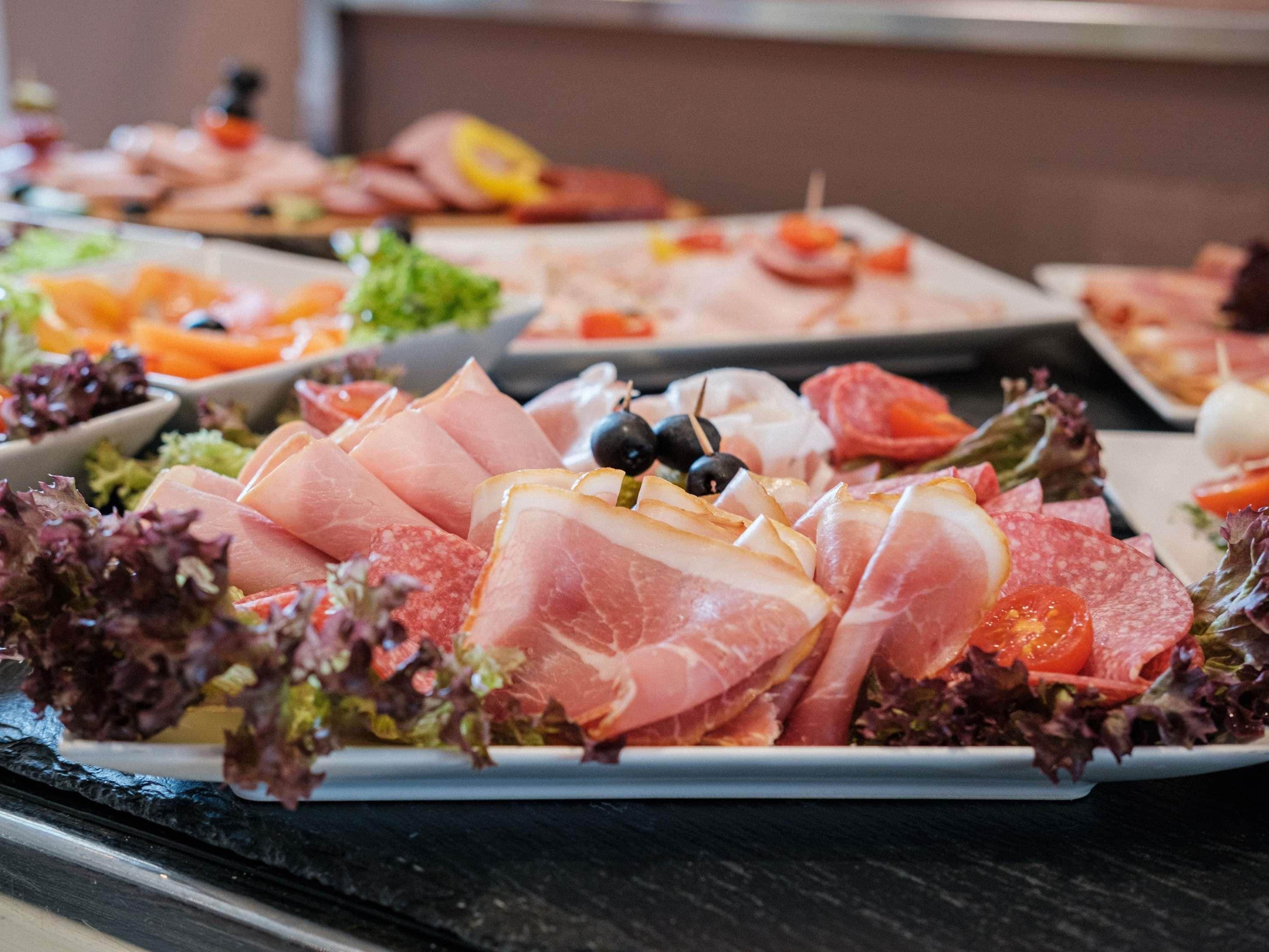 A variety of food items including sliced meats and vegetables on a buffet table.