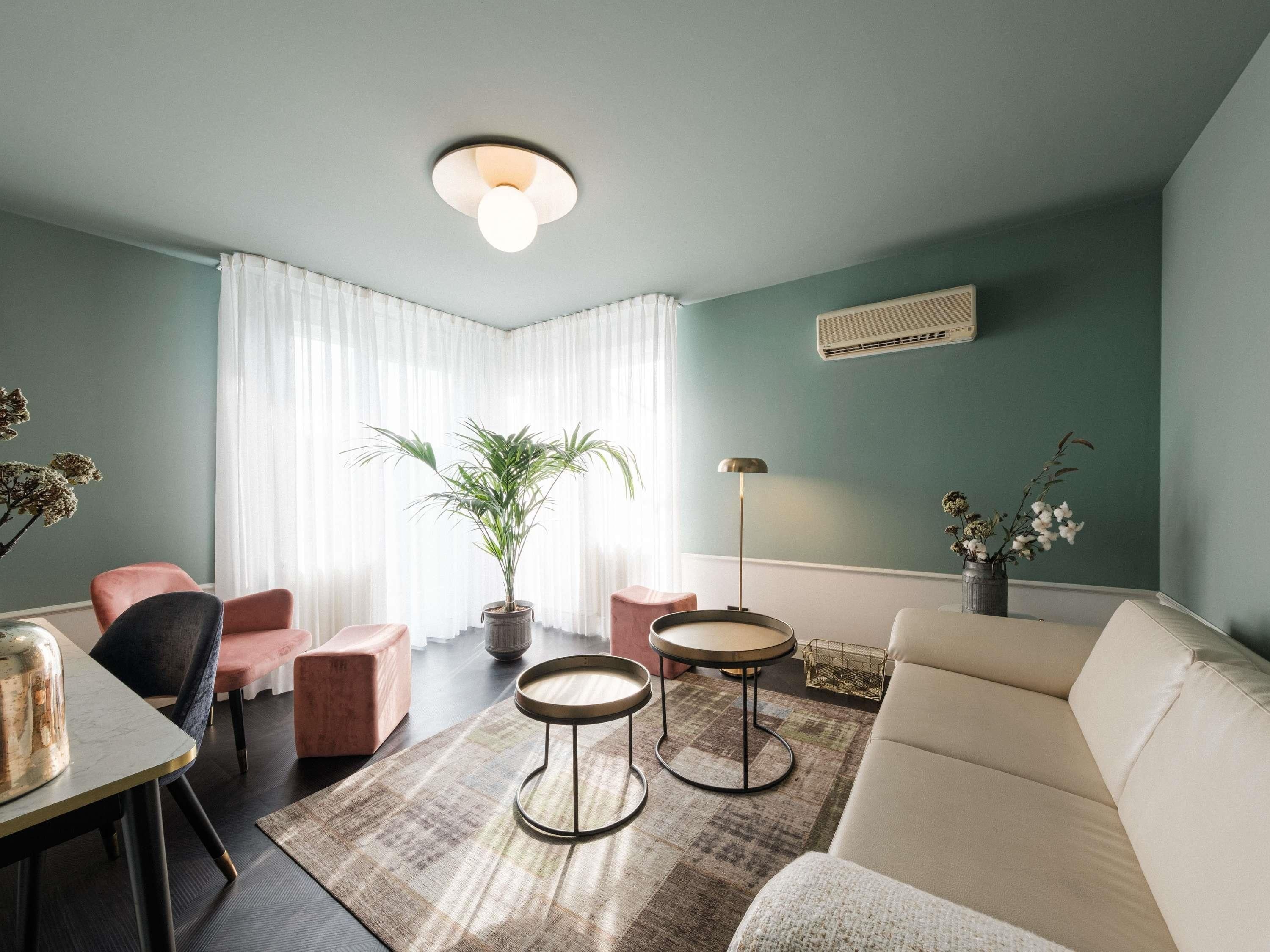 Una sala moderna con un sofá, dos sillones, una mesita, una planta en maceta y una lámpara de pie.