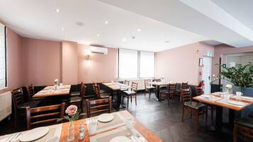 A restaurant with multiple dining tables, chairs, and a large window.