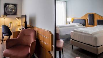 Ein Hotelzimmer mit Schreibtisch, zwei Betten, einem Sessel und einem Spiegel.