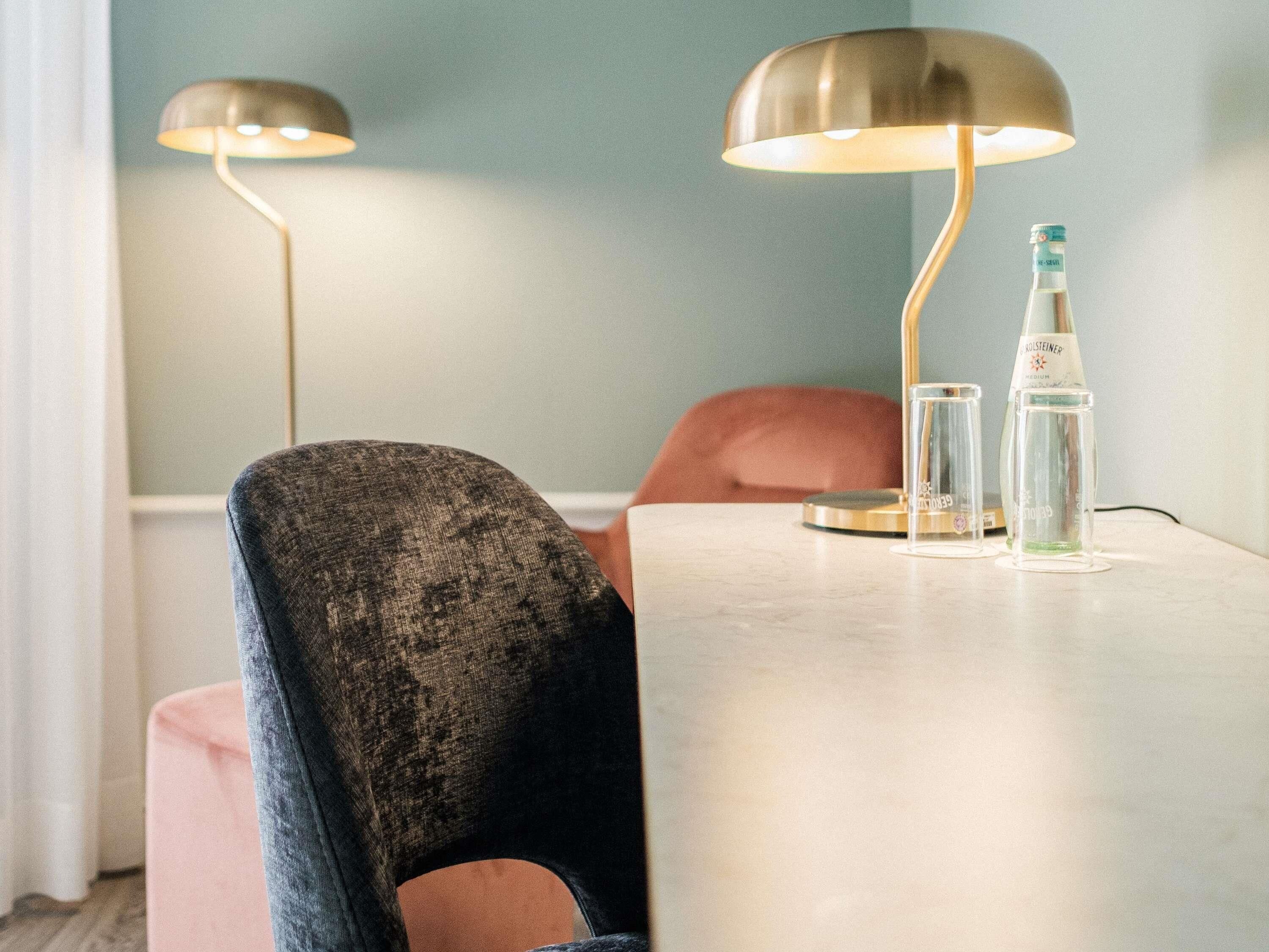 A dining table with two lamps, a bottle, and glasses.