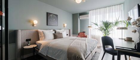 A modern bedroom with a bed, bedside tables, a desk, and a chair.