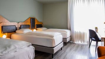 Habitación de hotel con dos camas, un escritorio, una silla y un ventanal con cortinas.