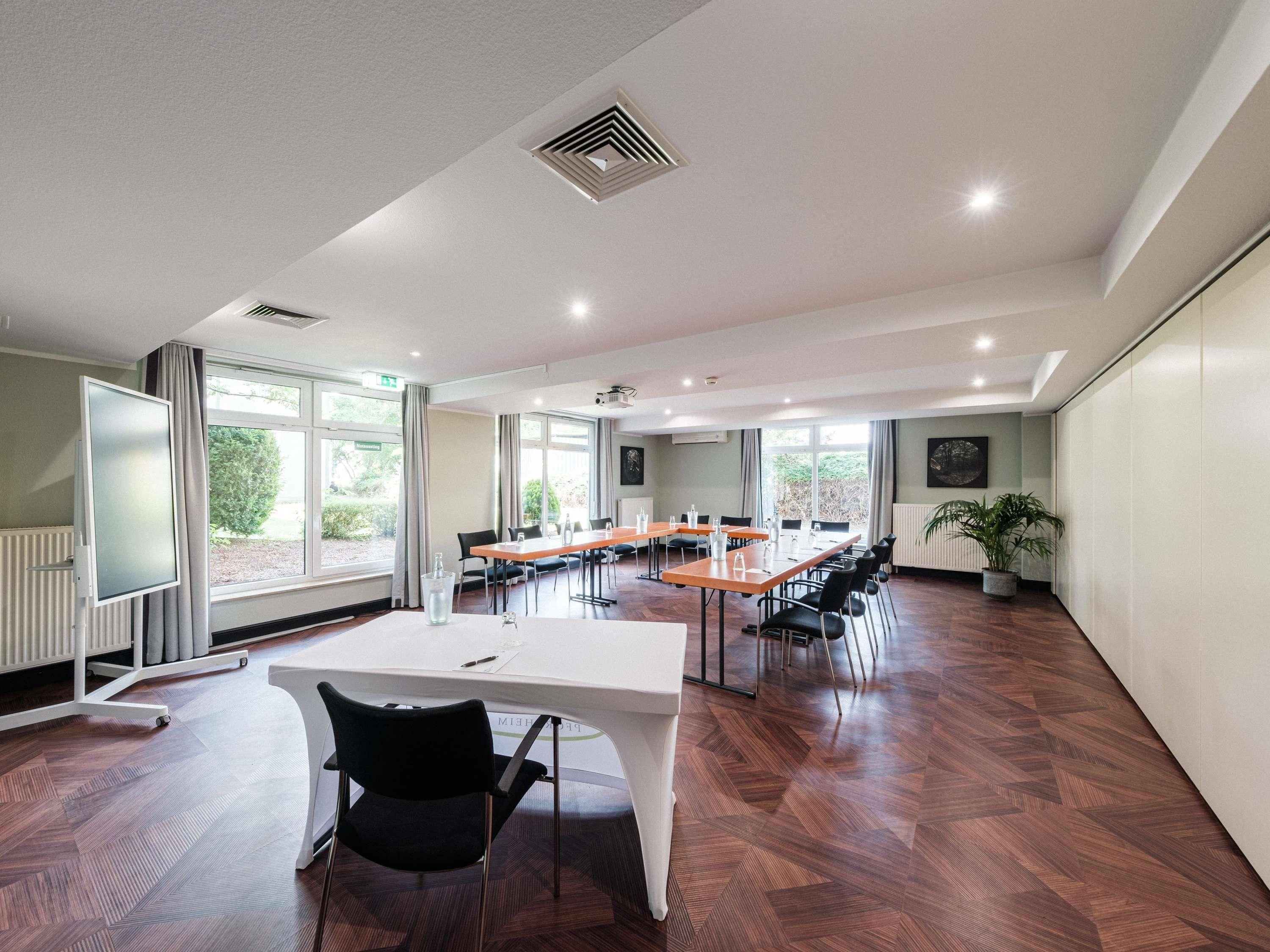 A conference room with a long table, chairs, a whiteboard, and large windows.