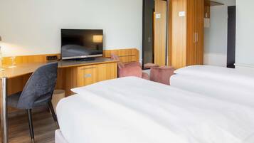 Une chambre d’hôtel comprenant un lit, un bureau avec une télévision, une chaise et une armoire.