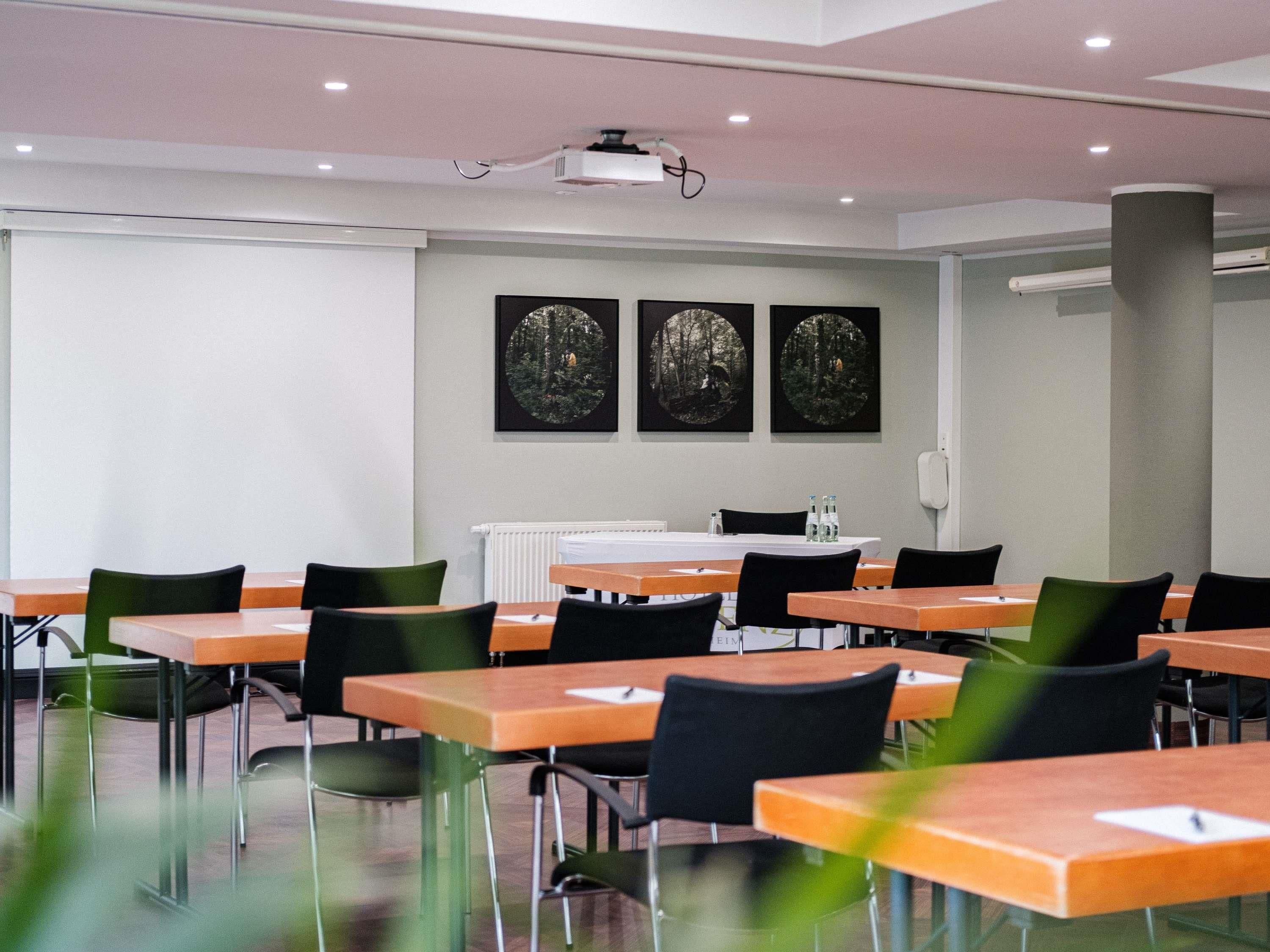 A conference room with tables and chairs, a projector, and framed pictures on the wall.
