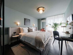Quarto moderno com cama, mesas de cabeceira, escrivaninha e uma cadeira.