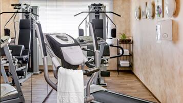 Un gimnasio con máquinas de cardio, una cinta de correr y equipo de pesas.