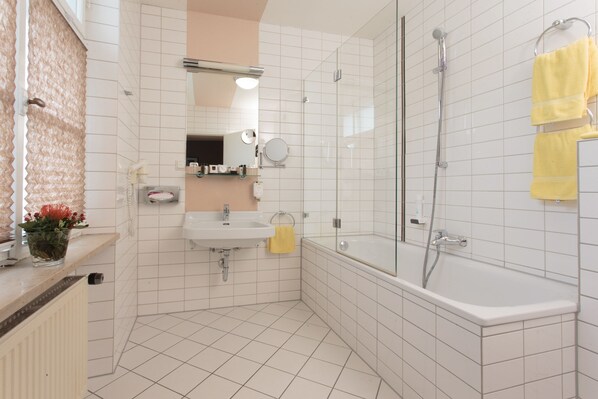 Un baño moderno con lavamanos, espejo y ducha.