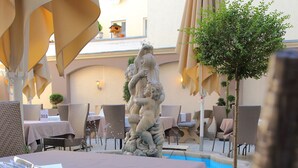 Un área de comedor al aire libre con mesas, sillas y sombrillas.