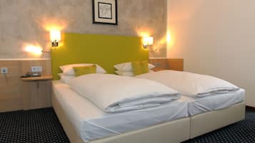 Una cama doble con ropa de cama blanca, un cabecero verde y dos lámparas de noche.