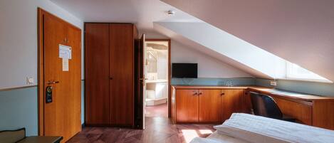 Une chambre d’hôtel équipée d’un lit, d’un bureau, d’une chaise et d’une armoire.