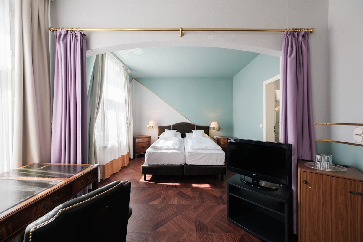 Ein Hotelzimmer mit einem Bett, einem Schreibtisch, einem Fernseher und einem Kleiderschrank.