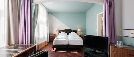 Una habitación de hotel con cama, escritorio, televisor y armario.
