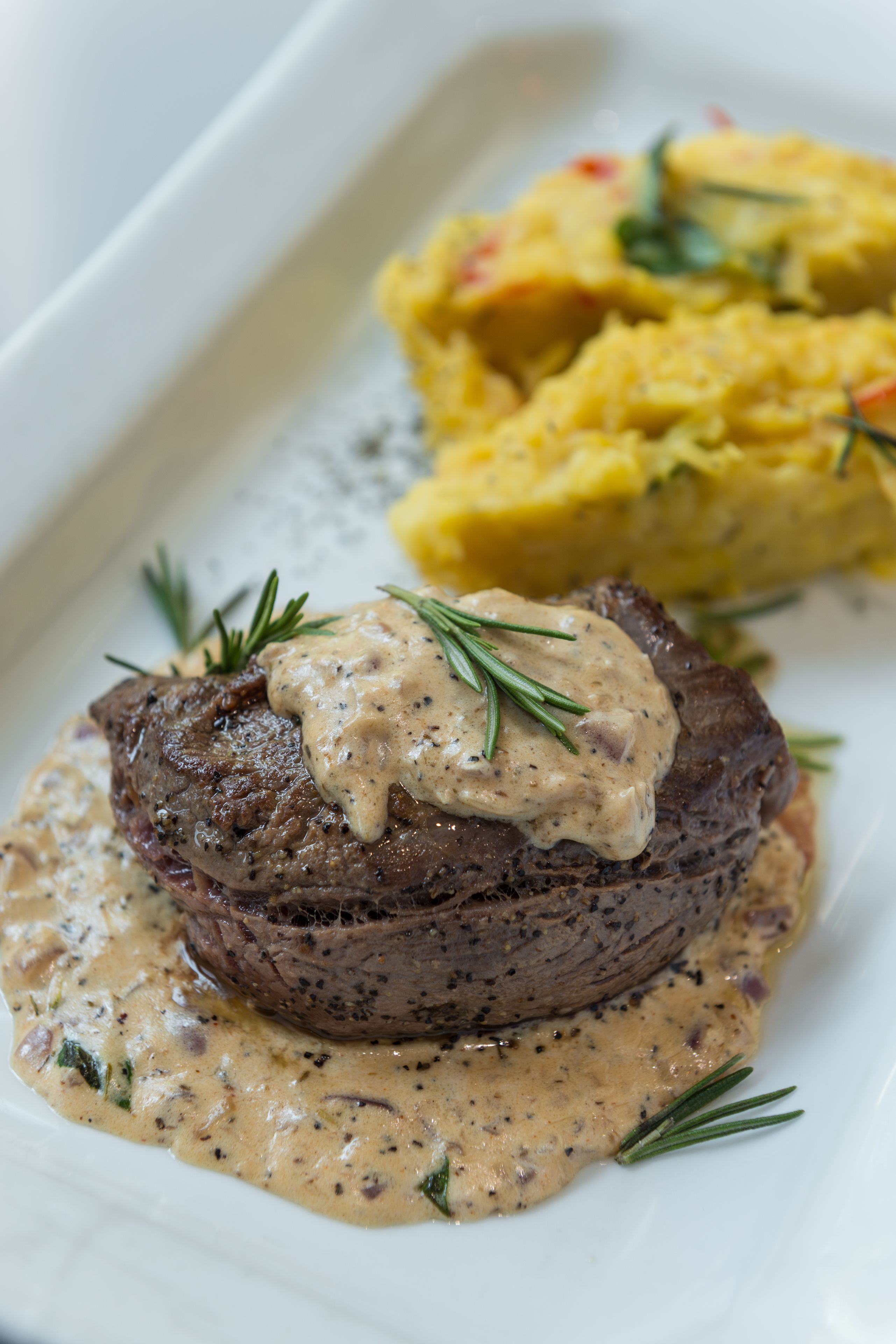A steak with a creamy sauce and a side of mashed potatoes.