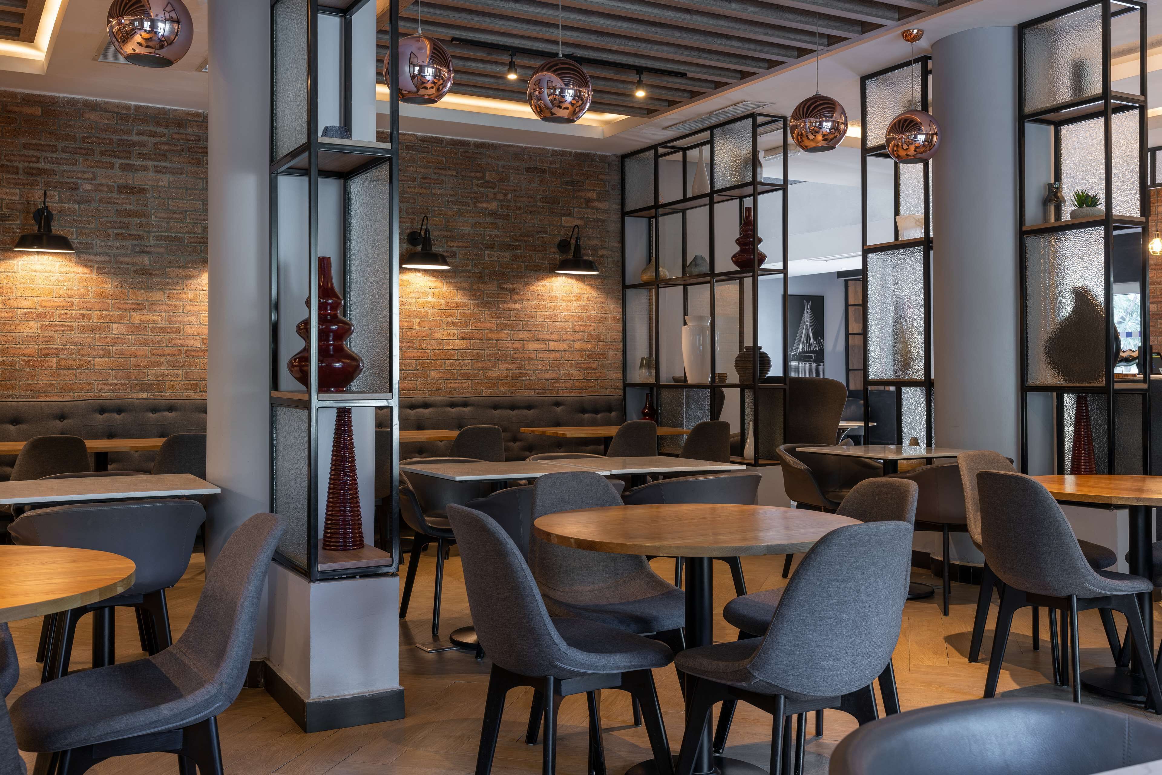 Un interno ristorante moderno con pareti in mattoni, tavoli rotondi e sedie contemporanee.
