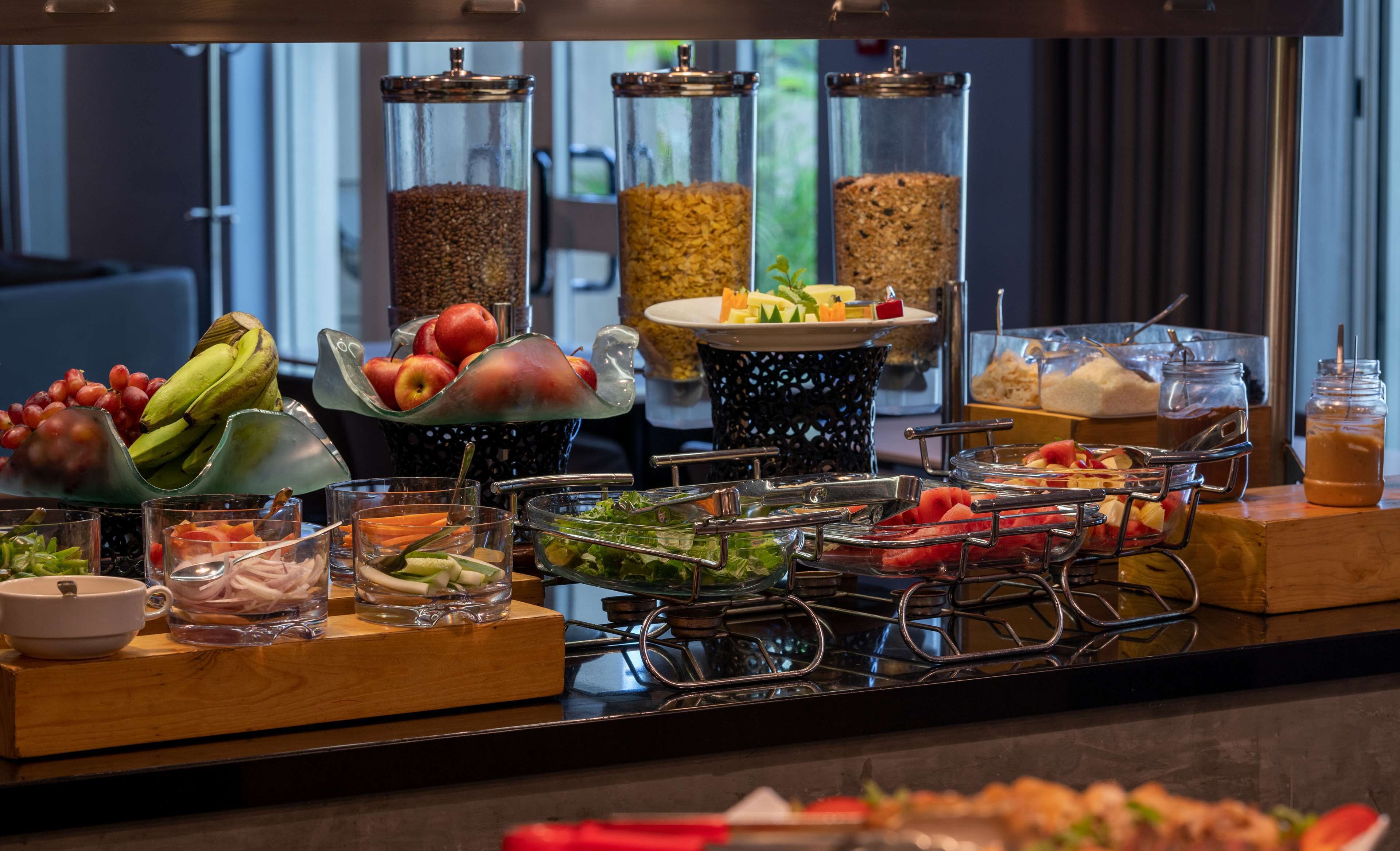 A buffet with various food items and beverages, including fruits, vegetables, and different types of grains.