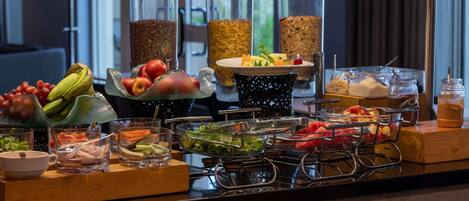 A buffet with various food items and beverages, including fruits, vegetables, and different types of grains.
